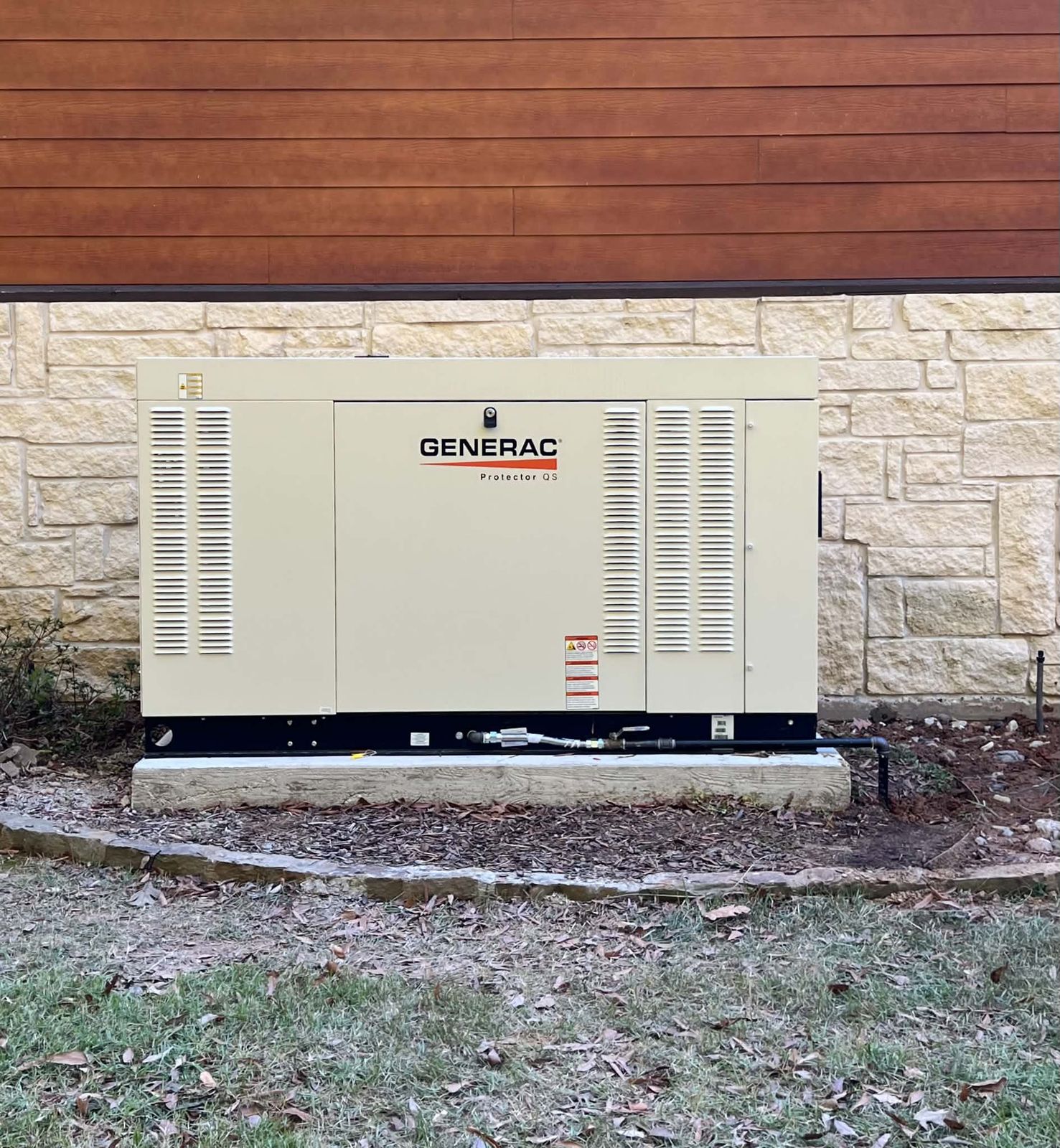 Generac standby generator installed against a stone wall